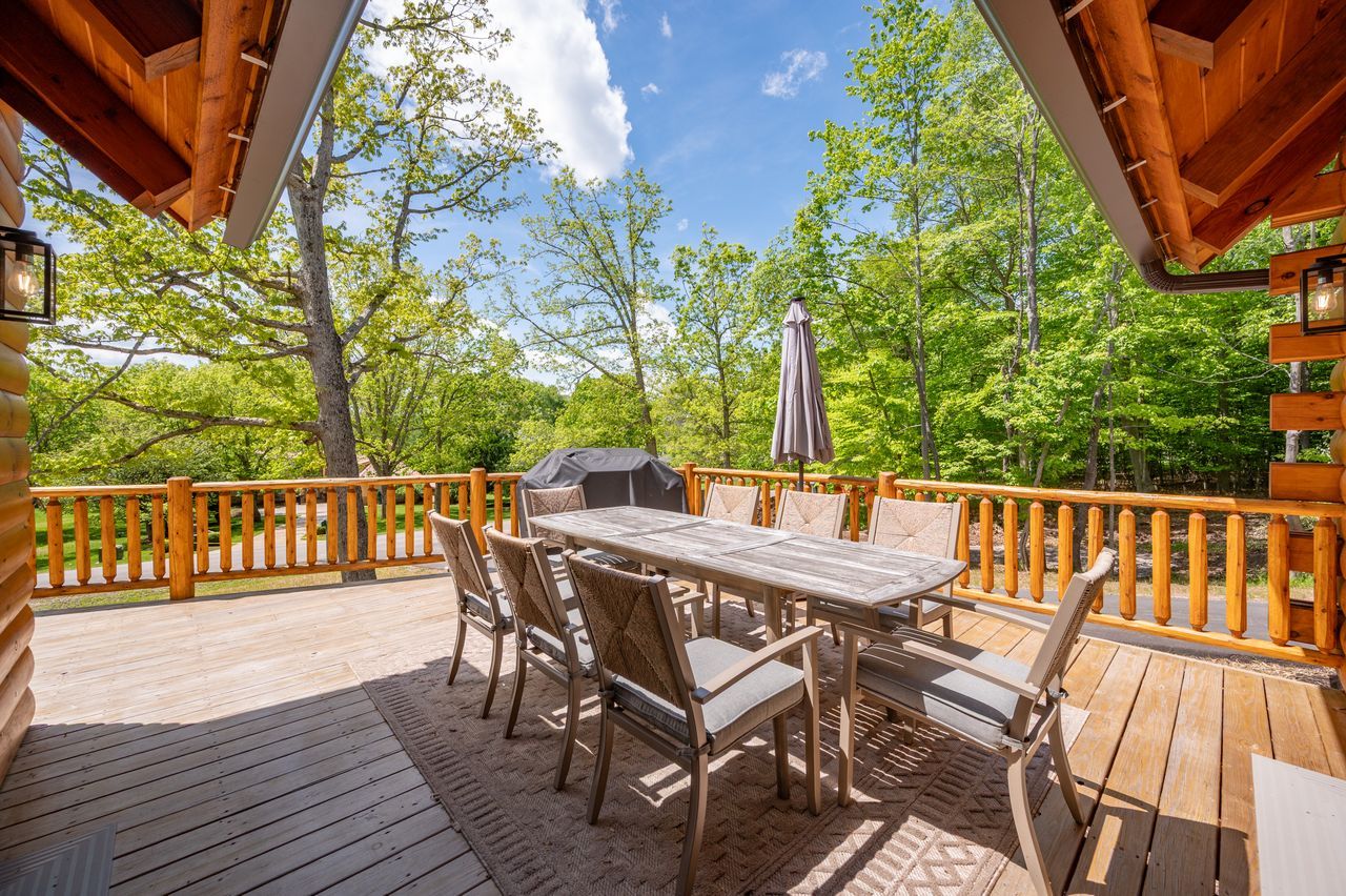 Covered deck with a dining table looking out into the trees